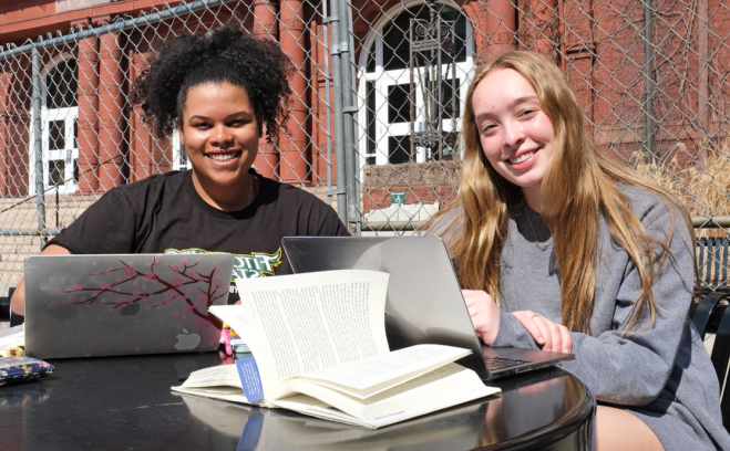 Students with laptops and books smiling near Thompson